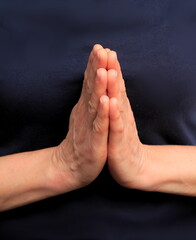 Obraz premium hands praying together on black background stock photo