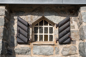 Fototapeta na wymiar Old window with solid wood shutters and a stone wall in the Alps in France
