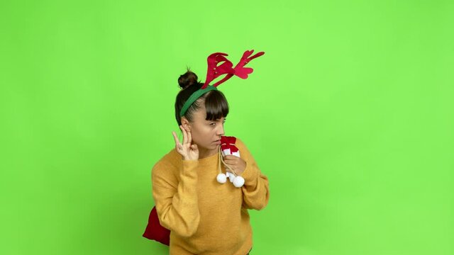 Young woman with christmas hat listening something over isolated background. Green screen chroma key