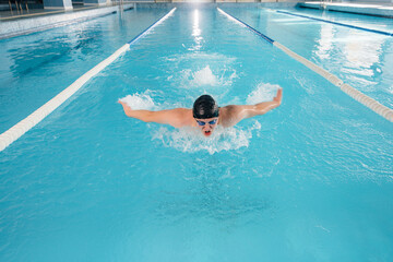 A young athlete trains and prepares for swimming competitions in the pool. Healthy lifestyle.