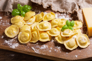 Fresh ravioli with green basil on wooden board