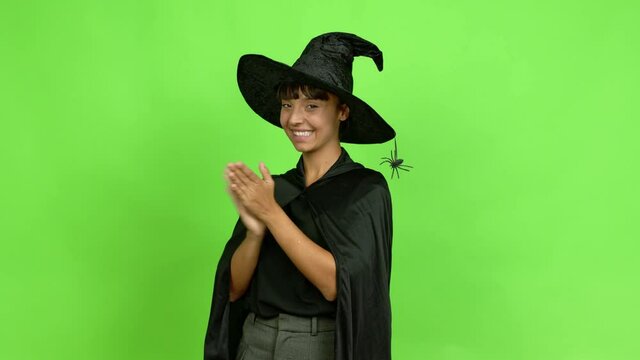 Young woman wearing witch hat for halloween parties applauding after presentation in a conference over isolated background. Green screen chroma key
