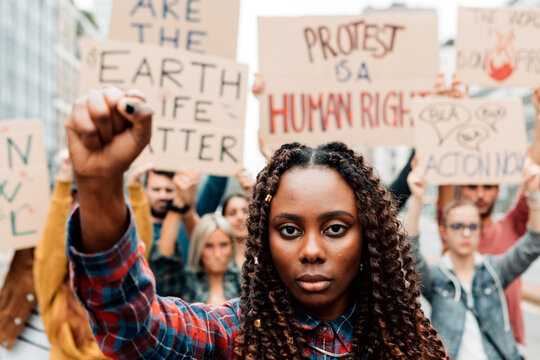 portrait of an african american woman with clenched fist in a global climate strike - group of young militants protesting against global warming