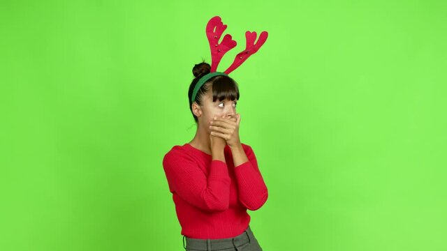 Young woman wearing christmas hat covering mouth with hands. Can not speak over isolated background. Green screen chroma key