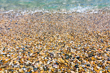 Small pebbles on the shore in a beach with wavy sea. Summer background photo. Pebble shore. Turkish riviera. Anamur Mersin Turkey.