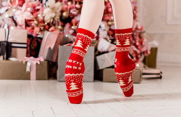 Ballerina's feet in pointe shoes with Christmas and New Year socks around decor and gifts