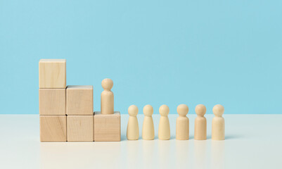 wooden figures of men on a ladder made of blocks. The concept of career advancement, starting at work, achieving goals
