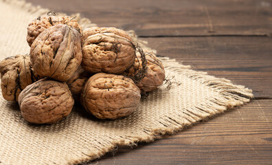 pile of inshell walnuts on a brown wooden table, autumn harvest