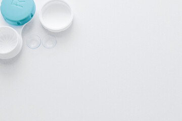 A container for lenses and two contact lenses lie on the side on a white background with space for text. top view, flat lay, copy space, isolate