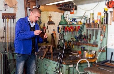 Portrait of professional craftsman engaged in repairing and assembling of shotgun in weapons workshop