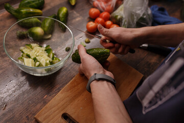 Hands cut cucumbers on the board.