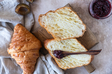 Delicious breakfast with fresh croissants, plum jam and juice on concrete background. Top view.