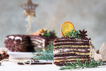 Chocolate layered cake decorated with rosemary, spices and dried orange slices. Festive Christmas or New Year decor. Russian honey cake, Medovik.