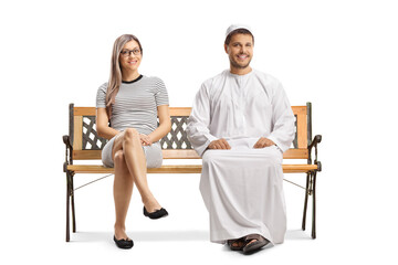 Young man in ethnic clothes sitting on a bench next to a casual young woman and smiling