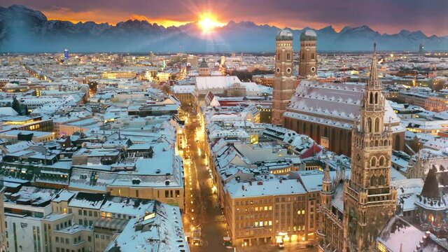 Beautiful munich city skyline aerial view at winter, munich drone footage germany covered with snow, fly over marienplatz town hall church frauenkirche at night.