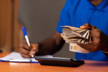african man holding come money and doing paperwork also