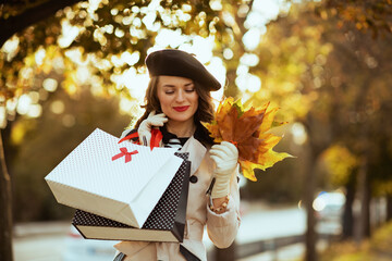 smiling woman with shopping bags and autumn leaves