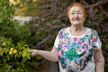 elderly woman against background of flowers in botanical garden with her beloved fruit