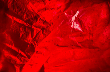 Abstract background made of red plastic bag and back lit flash light. Grunge texture. Vibrant colors. Minimal abstract background and pollution concept. With copy space.