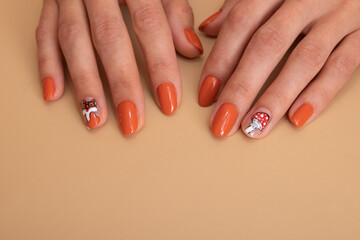 Female hands with orange manicure with a pattern under a glossy top