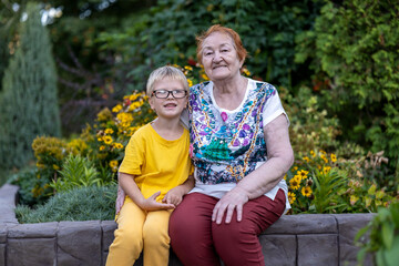 Fototapeta premium elderly woman on background of flowers in botanical garden with her beloved grandson