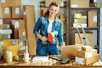 Portrait of smiling modern woman in jeans in warehouse
