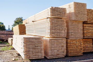 Stacked stacks of wooden planks against the sky. Lumber warehouse, wood drying. Lumber for construction.