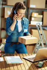 smiling young woman in jeans talking on smartphone in warehouse