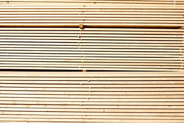 Background from wooden boards close-up. Stacked stacks of wooden planks. Lumber warehouse, wood drying, building material.