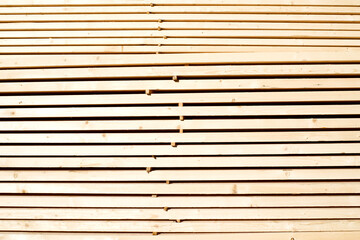 Background from wooden boards close-up. Stacked stacks of wooden planks. Lumber warehouse, wood drying, building material.