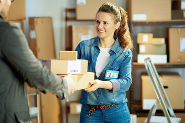 smiling young female in jeans in office giving parcel