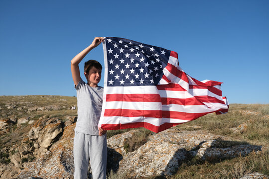 A boy holding waving US flag, beeng a patriot concept