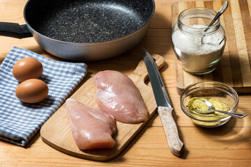 Chicken fillet on a cutting board ready for grilling. Raw chicken breast with grill pan, flour and spices. Chicken steaks for cooking