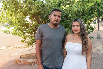 Portrait Of A Hispanic Couple In Front Of A Tree Outdoors.