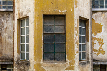 Fototapeta na wymiar Windows on facades of old properties demonstrate wear and tear caused by time