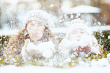 mom and child outdoors in city park in winter blowing snow