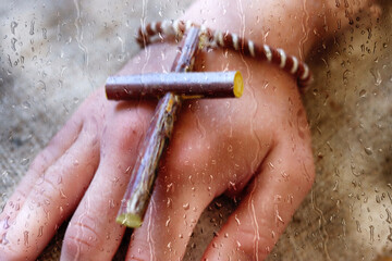 Rain, raindrops run down the glass window of the house, behind which is visible the blurry hand of...