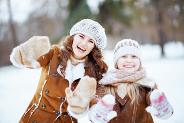 smiling elegant mother and child showing snowy mittens