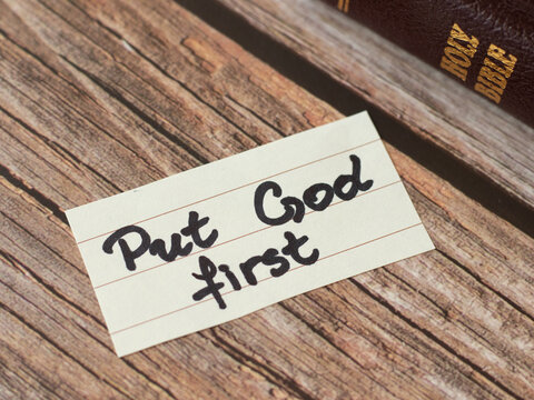 Put God Jesus Christ first. A handwritten quote from Scripture with closed Holy Bible Book. The biblical concept of obedience, love, praise, reverence. Faithful Christians obey and trust the LORD.