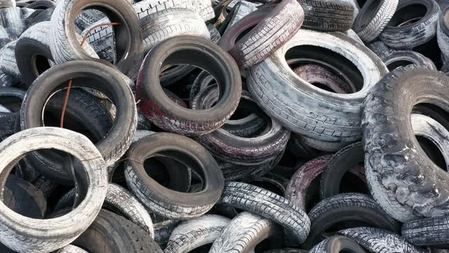 Pile of waste tires, dumped and ready for recycling. Heap of old scrap tyres, discarded and worn, painted white. Environmental protection and rubber pollution prevention. 