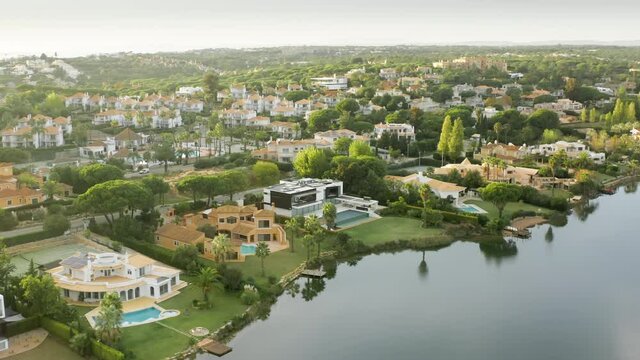 Overview of Quinta do Lago with luxury resorts in Almancil, Algarve, Portugal, Europe. Aerial shot of residential cottages located on banks of lake. Summer landscape on sunny day , 4k footage