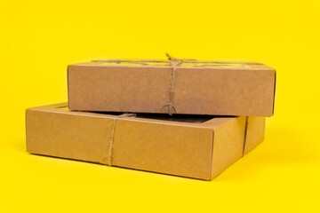 Cardboard recyclable boxes tied with a eco-friendly twine, for storage and delivery, on yellow background, copy space.