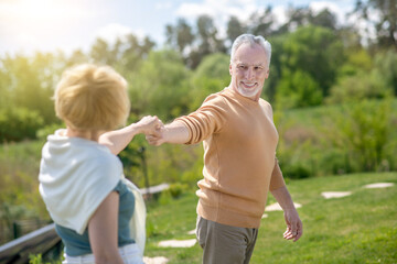 Fototapeta premium Joyous man taking his female dancing partner by the hand