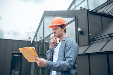Satisfied man in safety helmet looking at construction plan