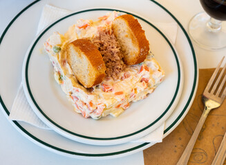 Ensalada rusa - salad with potatoes, tuna, green pea, olives and egg in a plate