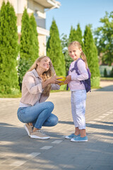 Joyful woman giving lunchbox to little girl