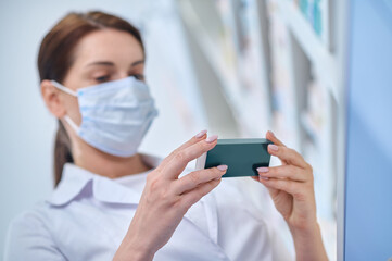 Woman in protective mask looking at pack of medicines