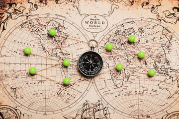 Fototapeta na wymiar Old compass on vintage world map with marked points