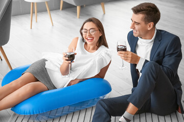 Happy colleagues drinking wine while dreaming about vacation in office