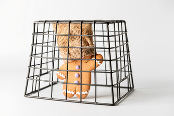 Cookie with sack on head in cage on light background. Concept of hostage